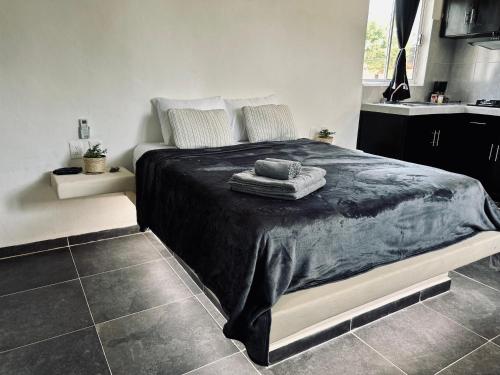 a bedroom with a large bed with a black blanket at Casa Tsunuum in Holbox Island