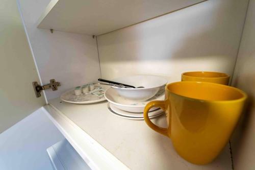dos tazas y platos en un estante en una cocina en Modern studio available close to the city, en Birmingham