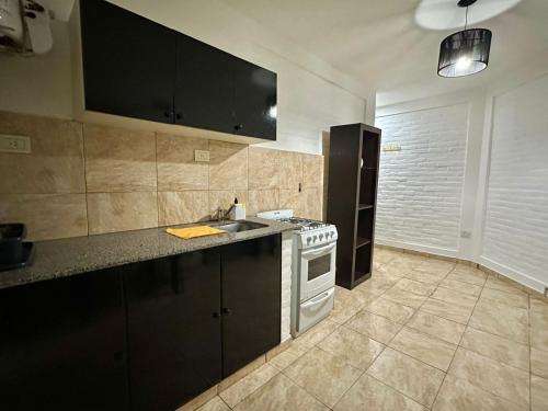 a kitchen with a stove and a sink in it at ACOGEDOR Dpto Pasaje Tucumán in Alta Gracia
