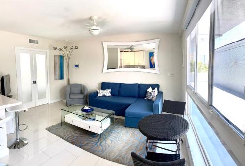 uma sala de estar com um sofá azul e uma mesa em Intracoastal sunsets condo building with 2 beds or 1 bed units private heated pool em Pompano Beach