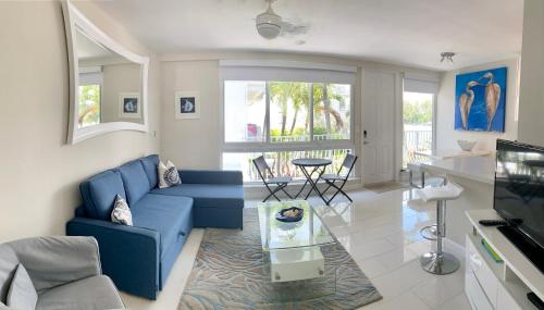uma sala de estar com um sofá azul e uma mesa de vidro em Intracoastal sunsets condo building with 2 beds or 1 bed units private heated pool em Pompano Beach