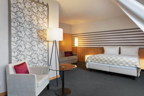 a bedroom with a bed and a chair and a table at Holiday Inn Vienna City by IHG in Vienna