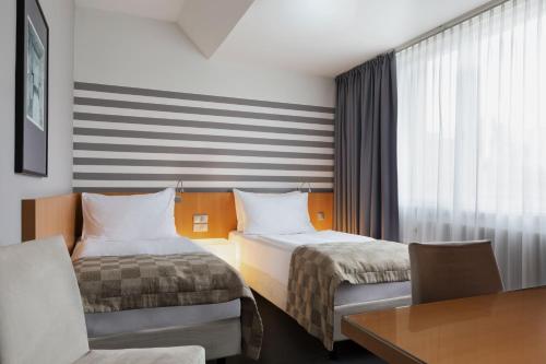 a hotel room with two beds and a desk at Holiday Inn Vienna City by IHG in Vienna