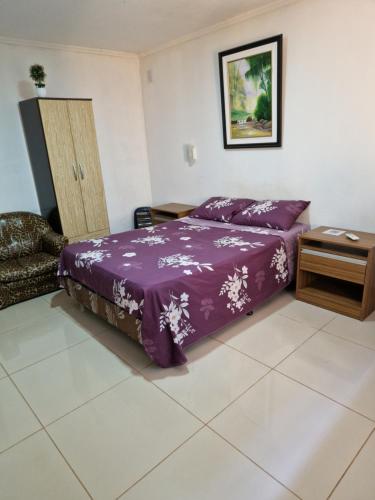 sypialnia z purpurowym łóżkiem i stołem w obiekcie Pacurí Hotel w mieście Puerto Iguazú