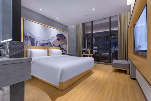 - une chambre avec un grand lit blanc et une télévision dans l'établissement Tuke China Hotel -Wenzhou South Bus Terminal, à Wenzhou