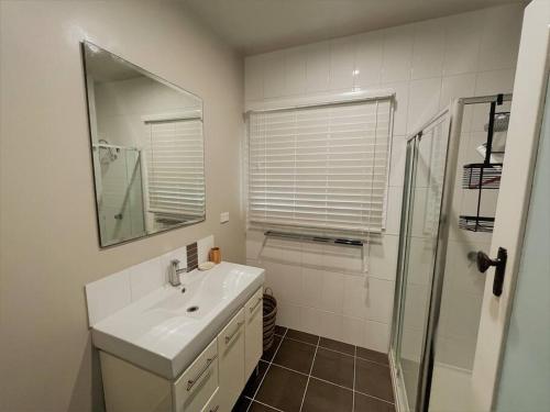 y baño blanco con lavabo y ducha. en Dempster House en Esperance