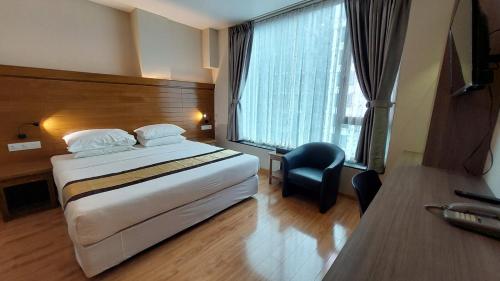 a hotel room with a bed and a desk and a window at Hotel Grand Galaxy in Yangon