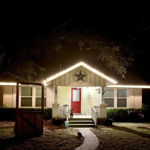 a white house with a red door at night at Pet Friendly Graham 2 Bedroom Home Christmas 365 at The Mistletoe Farm in Graham