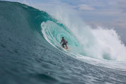 un homme faisant une vague sur une planche de surf dans l'océan dans l'établissement Krui Surfing, à Wainapal