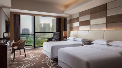 a hotel room with two beds and a large window at Sheraton Shunde Hotel in Shunde