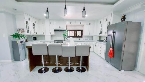 a kitchen with white cabinets and a island with bar stools at Trail Bedz Homestay in Baguio