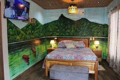 1 dormitorio con 1 cama con una pintura en la pared en Casa Cabaña En San Carlos Panamá en San Carlos