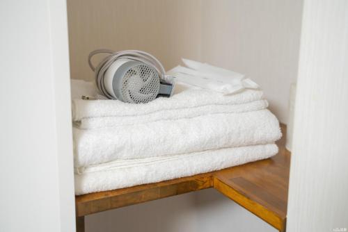 a pile of towels on a wooden shelf with a fan at W.K Inn in Osaka