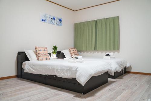 a bedroom with two beds and a green window at W.K Inn in Osaka