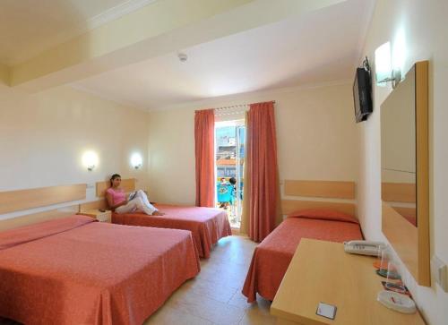 uma mulher sentada num quarto de hotel com duas camas em Dom Fernando II em Loulé