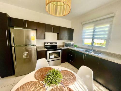 a kitchen with a table and a stainless steel refrigerator at Hermosa villa en Palma Real in La Ceiba