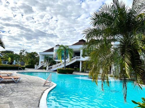 a resort swimming pool with a palm tree and a building at Hermosa villa en Palma Real in La Ceiba
