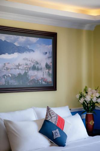 a bed with white pillows and a painting on the wall at Ladybird Boutique Hotel in Sa Pa