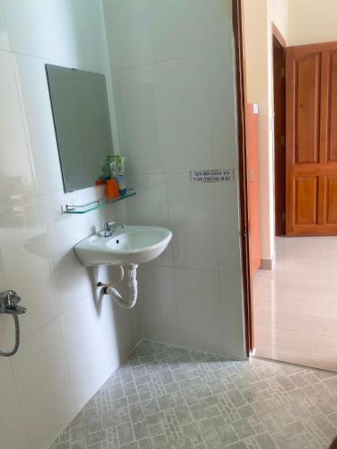 a white bathroom with a sink and a mirror at Nhà Nghỉ KHÁNH NGỌC in Vung Tau