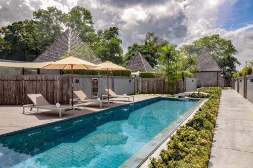 a swimming pool with chairs and umbrellas next to a fence at Tao Resort and Villas (SHA Extra+) in Phuket Town
