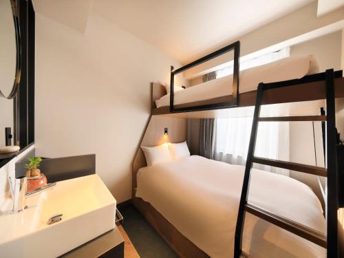 1 dormitorio con 2 literas y lavamanos en QuintessaHotel FukuokaHakata Relax&Sleep en Fukuoka