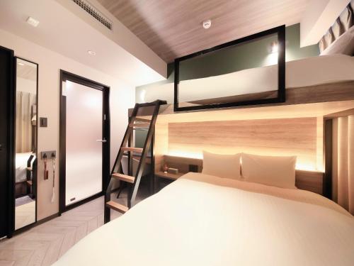 福岡市にあるQuintessaHotel FukuokaHakata Relax&Sleepのベッドルーム1室(ベッド1台、上部にテレビ付)