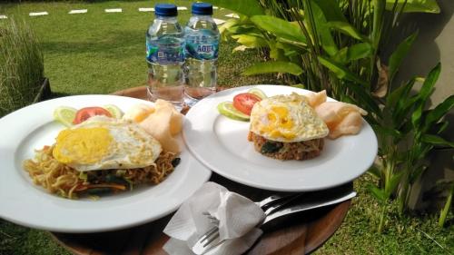 two plates of food on a table with bottles of water at Kubu River View in Ambengan
