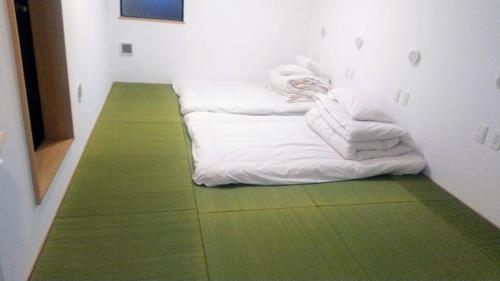 Pokój z białymi kocami i zieloną podłogą w obiekcie Hananogo Ikebukuro - Vacation STAY 16098v w Tokio