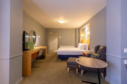a hotel room with a bed and a table at Holiday Inn Guildford by IHG in Guildford