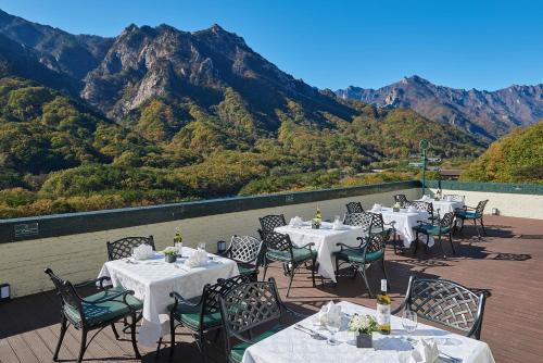 a restaurant with tables and chairs with mountains in the background at KensingtonHotel Seorak in Sokcho