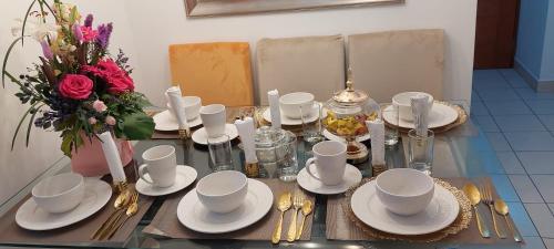 una mesa con platos y tazas y un jarrón de flores en C&G Home Perú, en Lima