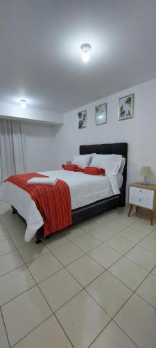 een slaapkamer met een bed met een rode deken erop bij C&G Home Perú in Lima