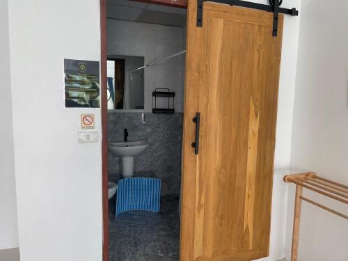 a bathroom with a wooden door and a sink at Skipper's Karon in Karon Beach