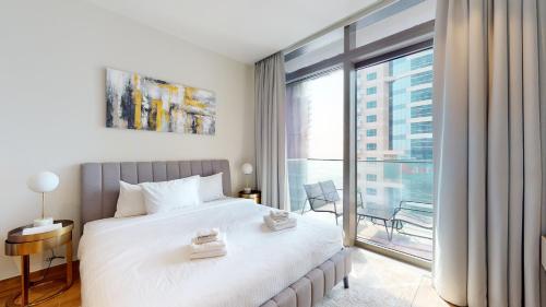 een slaapkamer met een groot bed en een groot raam bij Primestay - Jumeirah Living Marina Gate 1BR Prime Location with Waterfront Views Direct access to Marina Walk in Dubai