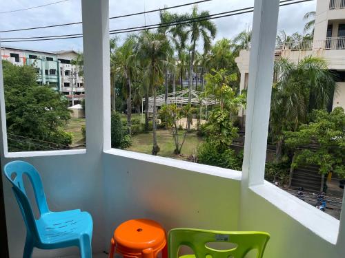 a room with two chairs and a window with palm trees at Skipper's Karon in Karon Beach