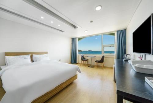 a bedroom with a bed and a desk with a television at VIEW Hotel Geoje in Geoje 