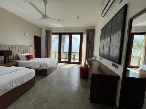 a hotel room with two beds and a large window at Driftwood Villa in Pamunugama