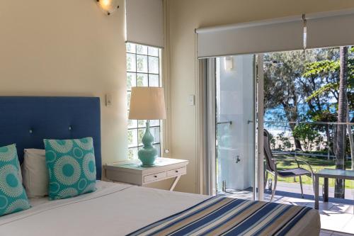 een slaapkamer met een bed, een tafel en een raam bij Beaches Holiday Apartments with Onsite Reception & Check In in Port Douglas