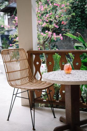 a table and a chair next to a table and flowers at Kresna By The Sea By Kresna Hospitality in Seminyak