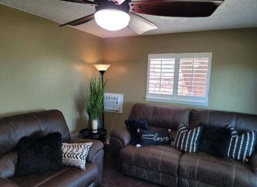una sala de estar con 2 sofás de cuero marrón y una ventana en Mountain View Lodging Cody, en Cody