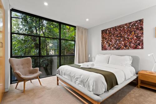 een slaapkamer met een groot bed en een groot raam bij Modern, Elegant Oasis - Trendy Area - Free Parking in Sydney