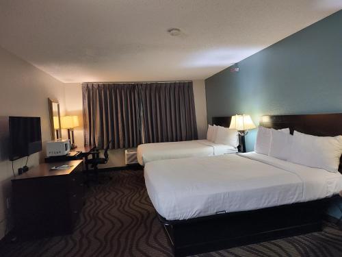 a hotel room with two beds and a television at Baymont Inn & Suites by Wyndham Lincoln NE in Lincoln