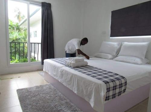 Ein Mann steht neben einem großen Bett in einem Zimmer in der Unterkunft Small Island Lodge in Vaadhoo