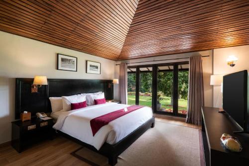 een slaapkamer met een groot bed en een groot raam bij Handara Golf & Resort Bali in Bedugul