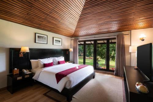 a bedroom with a large bed and a large window at Handara Golf & Resort Bali in Bedugul