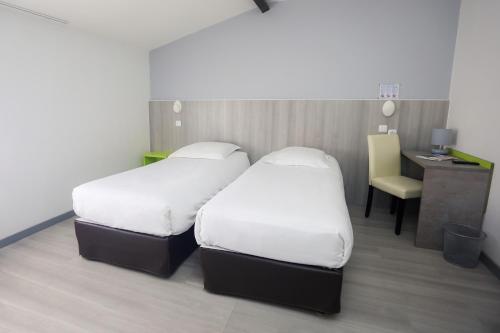 two beds in a room with a desk and a chair at Hôtel Le Cheval Blanc in Saint-Maixent-lʼÉcole