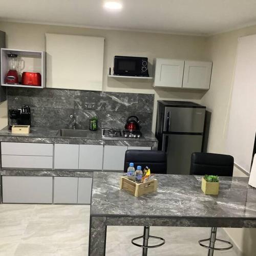 a kitchen with a marble counter top with chairs and a refrigerator at Cozy 1-bedroom apartment minutes away drive to Mangel Halto Beach in Savaneta
