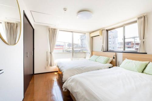 two beds in a room with two windows at FUJIMI TOWN HOUSE in Tokyo