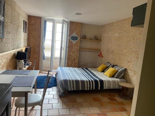 a bedroom with a bed and a table and a kitchen at Les portes du marais in Benet