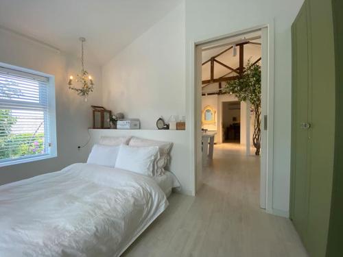 a bedroom with a white bed and a hallway at Gonae Reborn in Jeju